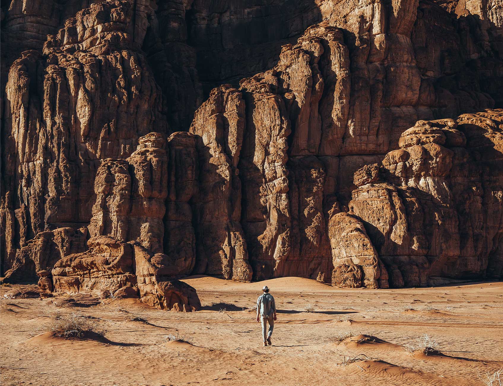Man walking towards rocky mountain